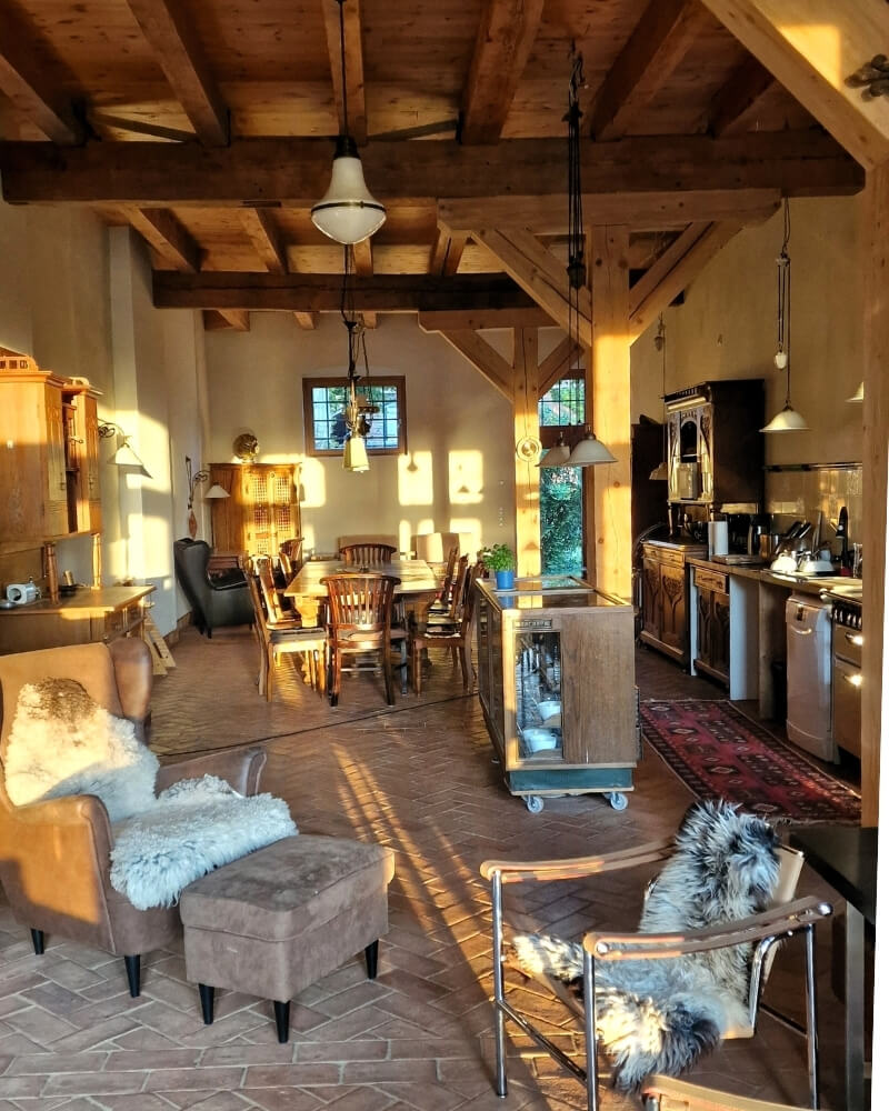 Offene Küche im Scheunenloft Usedom mit Holztisch, sichtbaren Balken und gemütlichen Sesseln