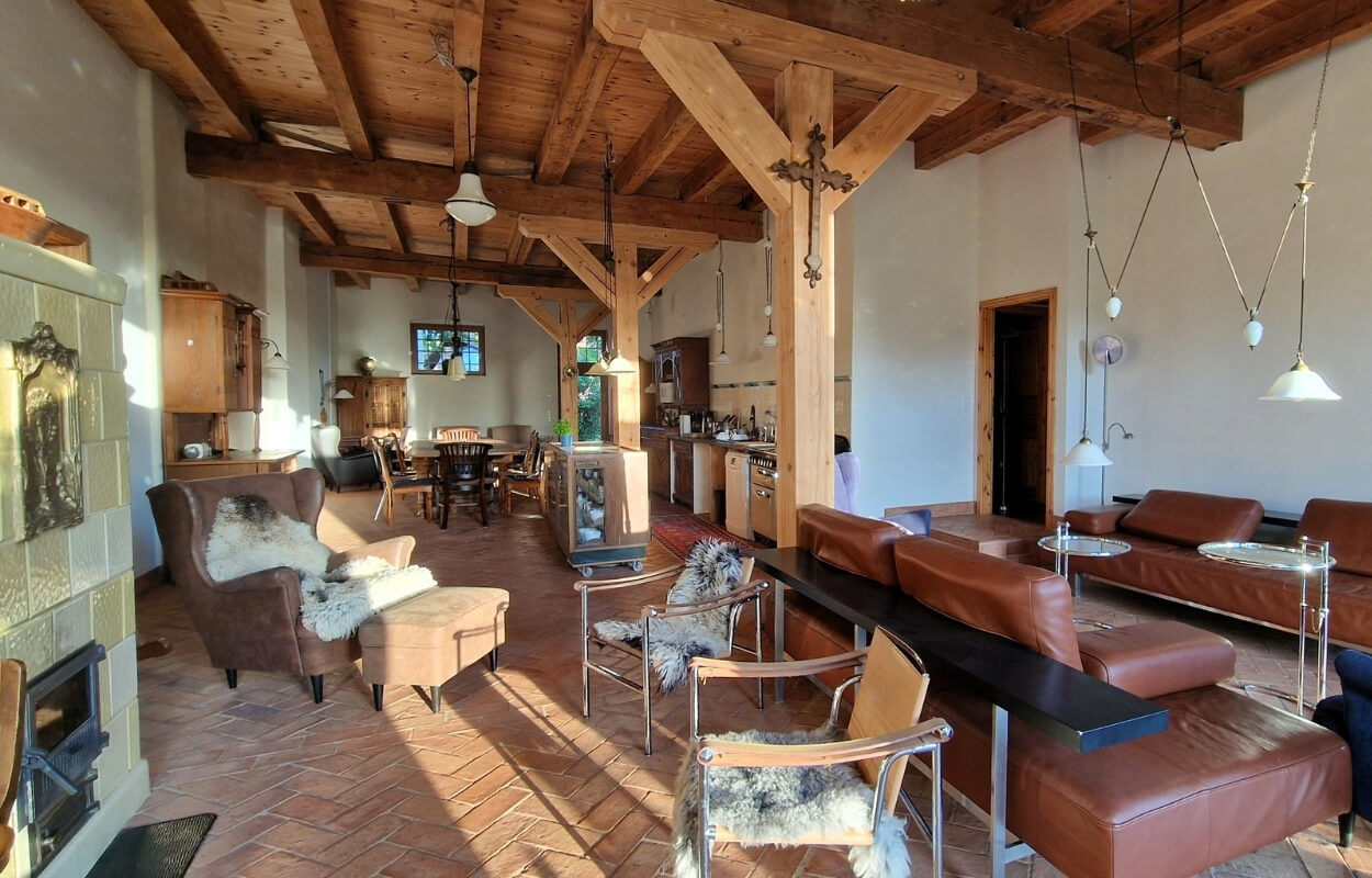 Offener Wohn- und Essbereich im Scheunenloft Usedom mit Kachelofen, Holzbalken und gemütlicher Einrichtung