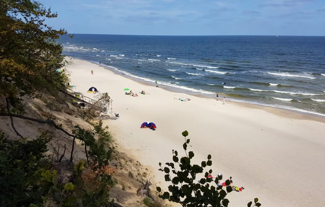 Weißer Sandstrand auf Usedom mit sanften Wellen und Badegästen im Sommer